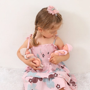 Detailed close-up of 8-inch mini reborn dolls in knit outfits on a white plush rug