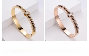 Detail view of gold and rose gold titanium bracelets with crystals on stone stand