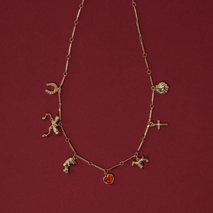 Detail of vintage gold-plated necklace charms including red gemstone heart and horseshoe