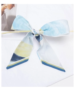 Detail of blue and yellow bow-shaped silk scarf tied on a wooden stand with abstract print