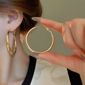 Close-up of polished gold hoop earrings featuring a classic clasp and mirror finish