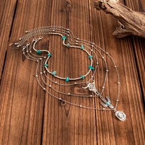 Detail of bohemian necklace set with turquoise cactus and cow skull pendants