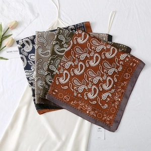 Detail view of paisley pattern silk scarves in navy, grey, green and brown colors