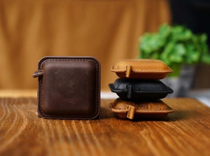 Close-up of vintage leather mini tape measures in dark brown and black on wood