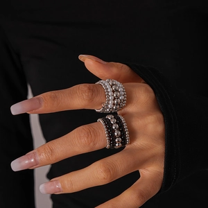 Detailed view of multilayer beaded rings in silver and black on model's fingers