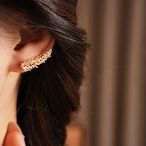 Detail of elegant gold ear cuff with wheat-ear pearls and sparkling zircons on ear