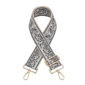 Detail of adjustable jacquard paisley strap with light gold metal swivel hooks and buckles