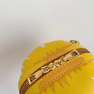 Detail shot of the golden metal zipper and stitching on the yellow round smiley bag