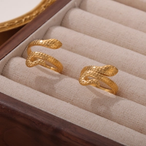Golden snake-shaped wrap ring with scale texture displayed on wooden jewelry box