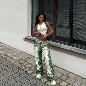 Close-up of green textured wide-leg trousers and a white knit vest in urban street style