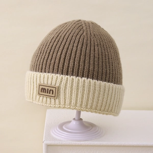 Detail of winter knit beanie with color-block design and min leather patch accent