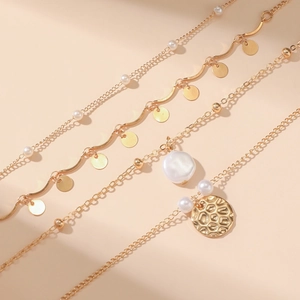 Detailed view of gold multi-layer necklace with baroque pearls and hammered coin pendant