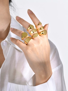 Close-up of polished gold signet rings in geometric shapes including circle and heart