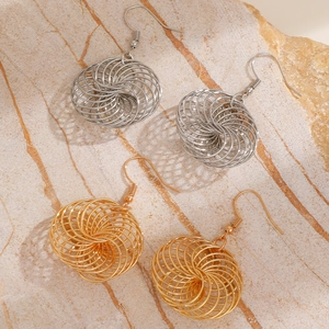 Detailed close-up of hollow bird nest earrings in gold and silver on stone