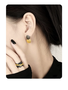 Detailed view of irregular textured black and gold sterling silver earrings and ring set