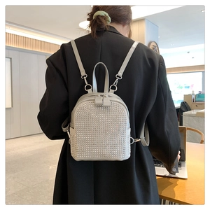 Macro detail of shimmering rhinestone inlay on a light gray mini fashion backpack for women