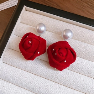 Macro shot of velvet red rose earrings with sparkling crystals and elegant white pearls