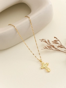 Detailed close-up of a gold-plated cross necklace with intricate openwork and micro-dots