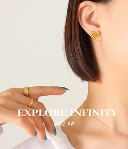 Detail of gold-plated heart earrings and quilted rings on model with necklace