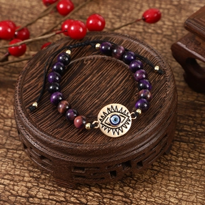 Detail of beaded evil eye bracelet featuring purple stones and adjustable braided cord