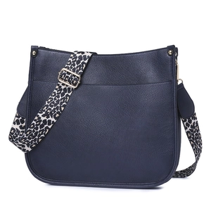 Detail of navy blue textured leather crossbody bag with a wide leopard print strap