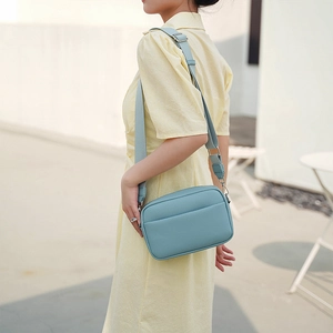 Detail of blue PU square bag with litchi texture and wide fabric shoulder strap