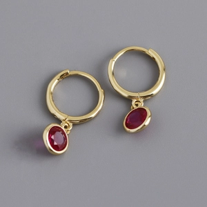 Detail of gold S925 sterling silver hoop earrings with round red zircon stone pendant