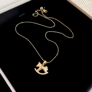 Gros plan d'un collier pendentif cheval doré dans un coffret cadeau en velours noir