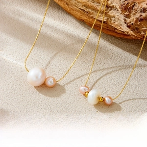 Detailed view of irregular white and pink pearls on a gold stainless steel chain