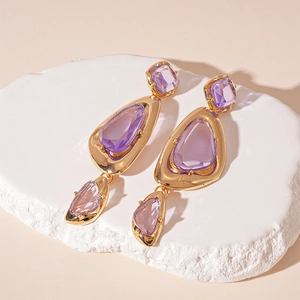 Detail of vintage geometric earrings with purple gems and gold plated frames