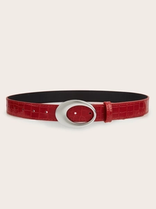 Detail of red crocodile texture leather belt with a silver oval buckle for jeans