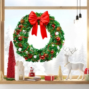 Christmas wreath with green pine needles, red bow and ornaments hanging on a window