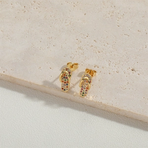 Minimalist gold flip-flop stud earrings with colorful zircon stones on stone surface