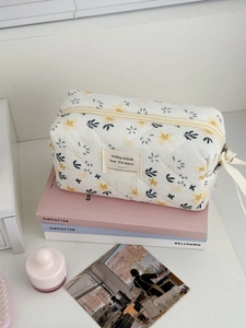 Close-up of floral corduroy makeup bag with diamond quilting and vintage text label