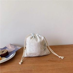 Close-up of floral embroidery on cotton linen drawstring storage bag on a wooden table