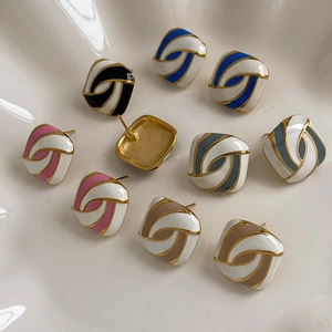 Square enamel stud earrings with golden swirls in macaron candy colors set on a white tray