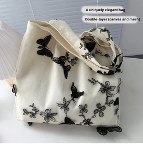 Detail of double-layer canvas tote featuring butterfly embroidery and black mesh overlay