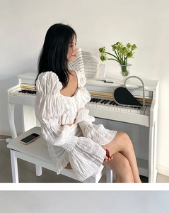 Elegant white two-piece set with puffed sleeves and textured fabric on a piano scene