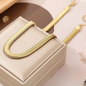 Elegant gold snake bone chain necklace displayed on a jewelry box with aesthetic props