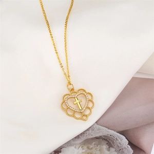 Close-up of golden heart pendant with hollow cross and shimmering zircon inlay on white lace