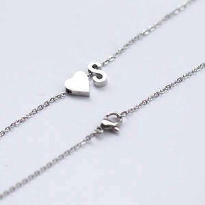 Detailed shot of silver stainless steel necklace with heart and letter S pendants