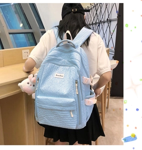 Détail du sac à dos bleu clair à texture gaufrée avec porte-clés peluche lapin blanc