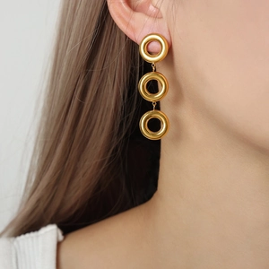 Minimalist triple-loop gold-plated titanium geometric drop earrings worn by a model