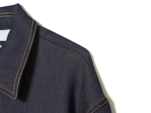 Gros plan détaillé du tissu denim bleu foncé avec coutures orange contrastées et texture sergé