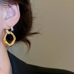 Close-up of gold geometric drop earrings with sparkling small diamonds on model