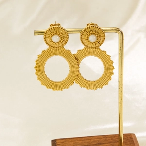 Detail of bohemian gold hoop earrings with sunburst pattern and pearl on a metal display