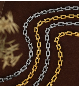 Detail view of 18k gold and silver cuban link necklaces on dark brown velvet surface