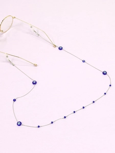 Detail of silver chain eyewear strap with blue evil eye beads on purple background