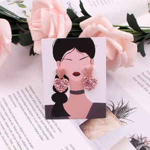 Detailed view of pink double-layered heart stud earrings with rhinestones on a display card