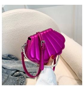 Detailaufnahme der metallic-pinken Muschel-Handtasche mit dekorativem Perlenhenkel